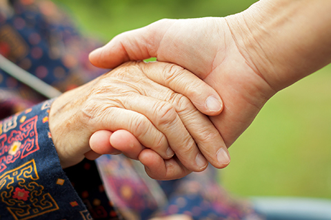 Carer holding a older lady's hand